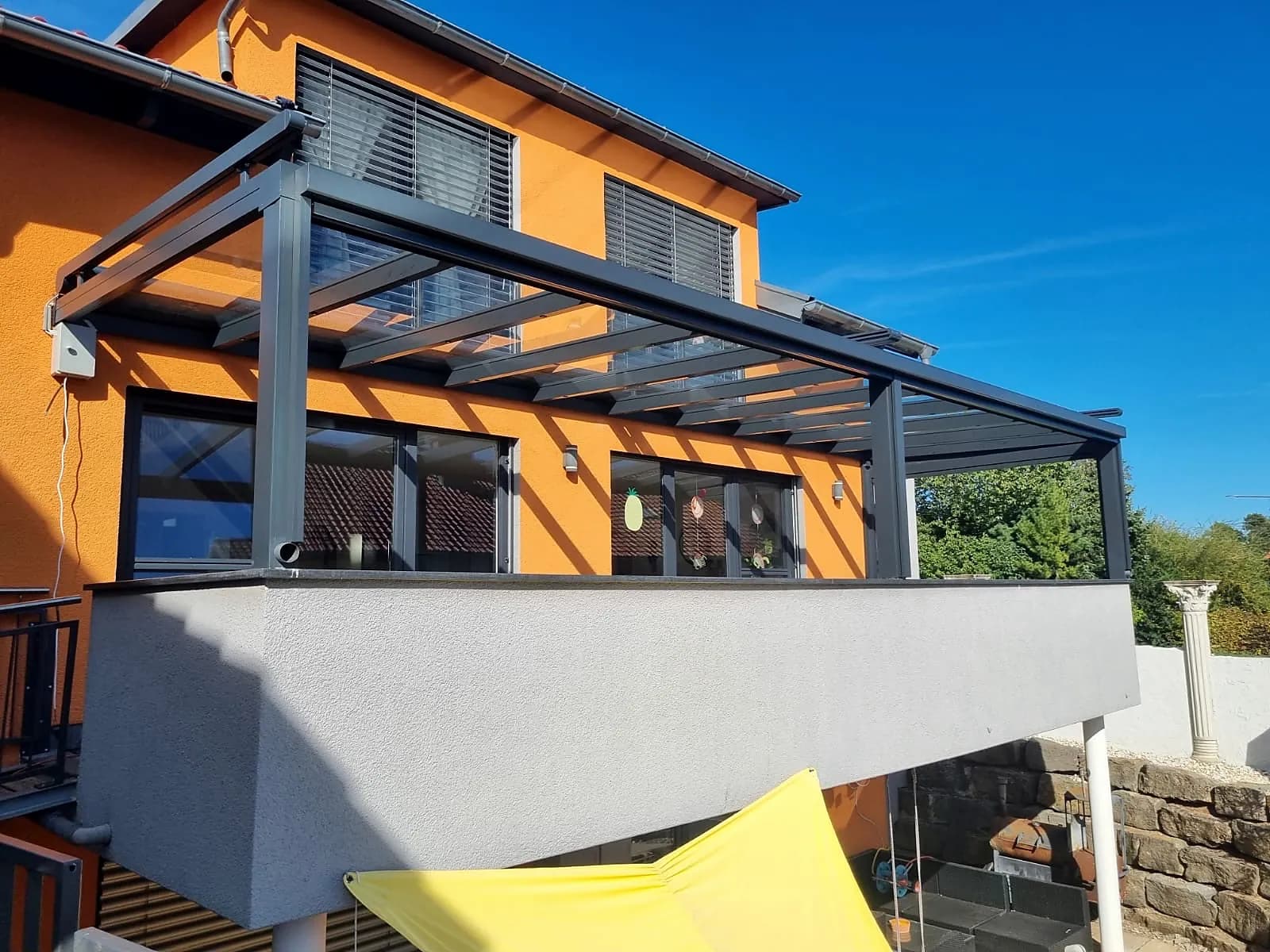 Balkonüberdachung aus Glas und Aluminium an einem Wohnhaus