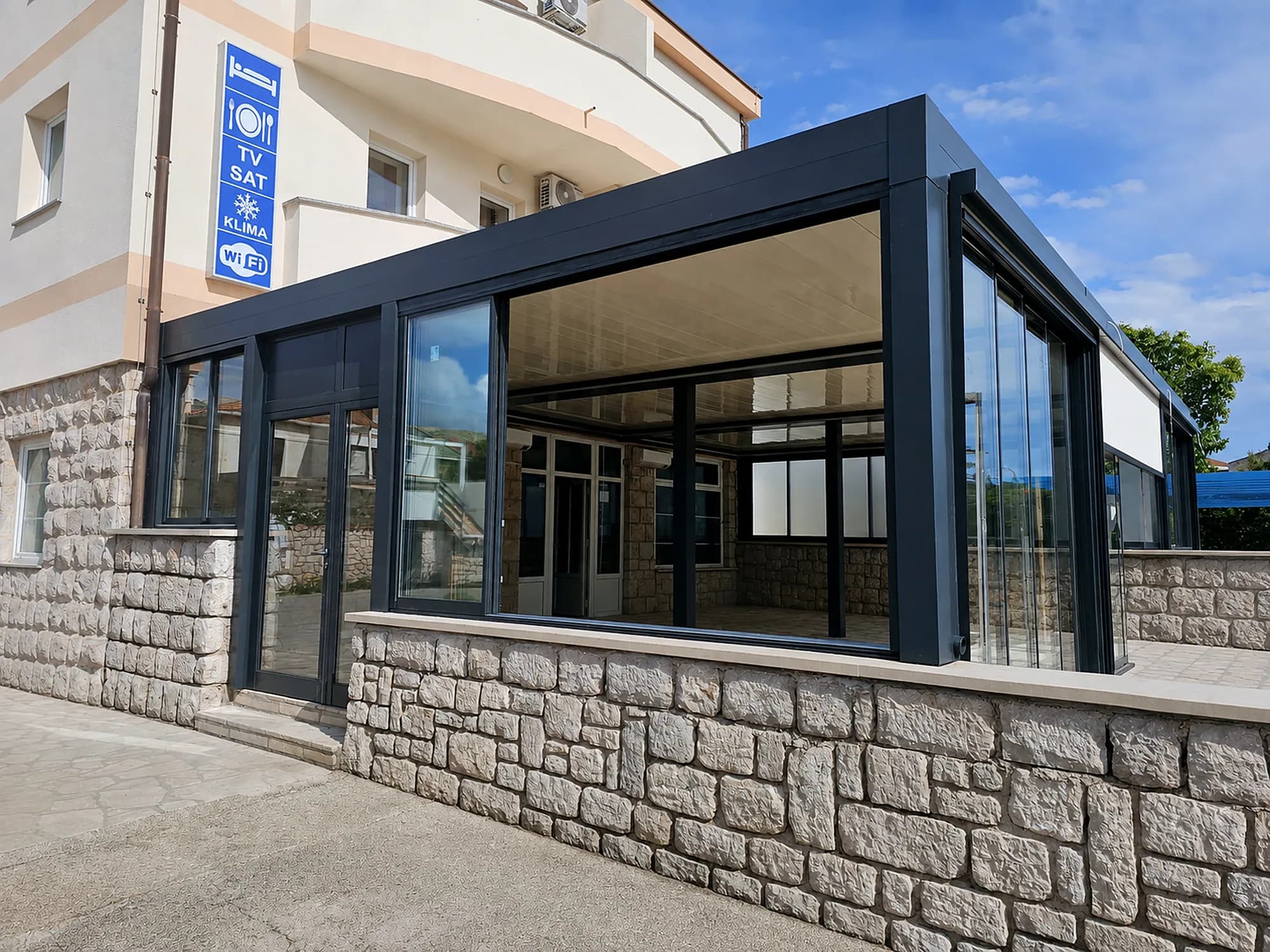 Glashaus auf einem Natursteinsockel an einem Hotel