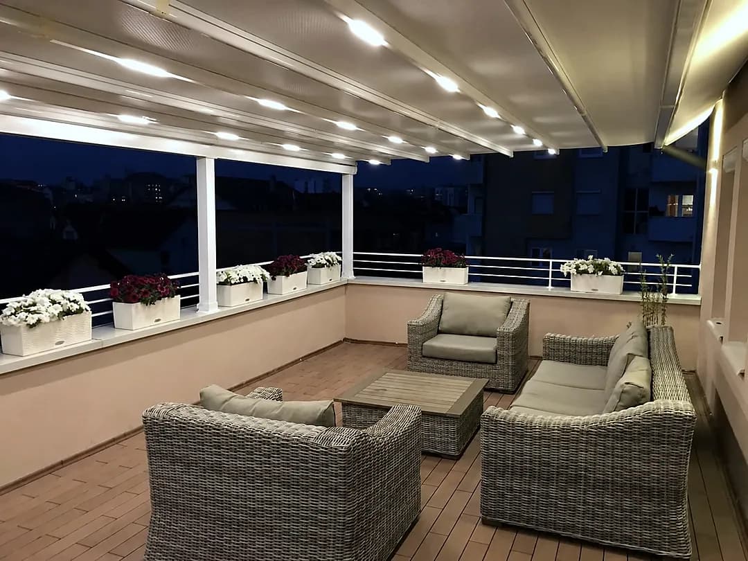 Pergola mit Beleuchtung und Lounge auf einer Dachterrasse bei Nacht