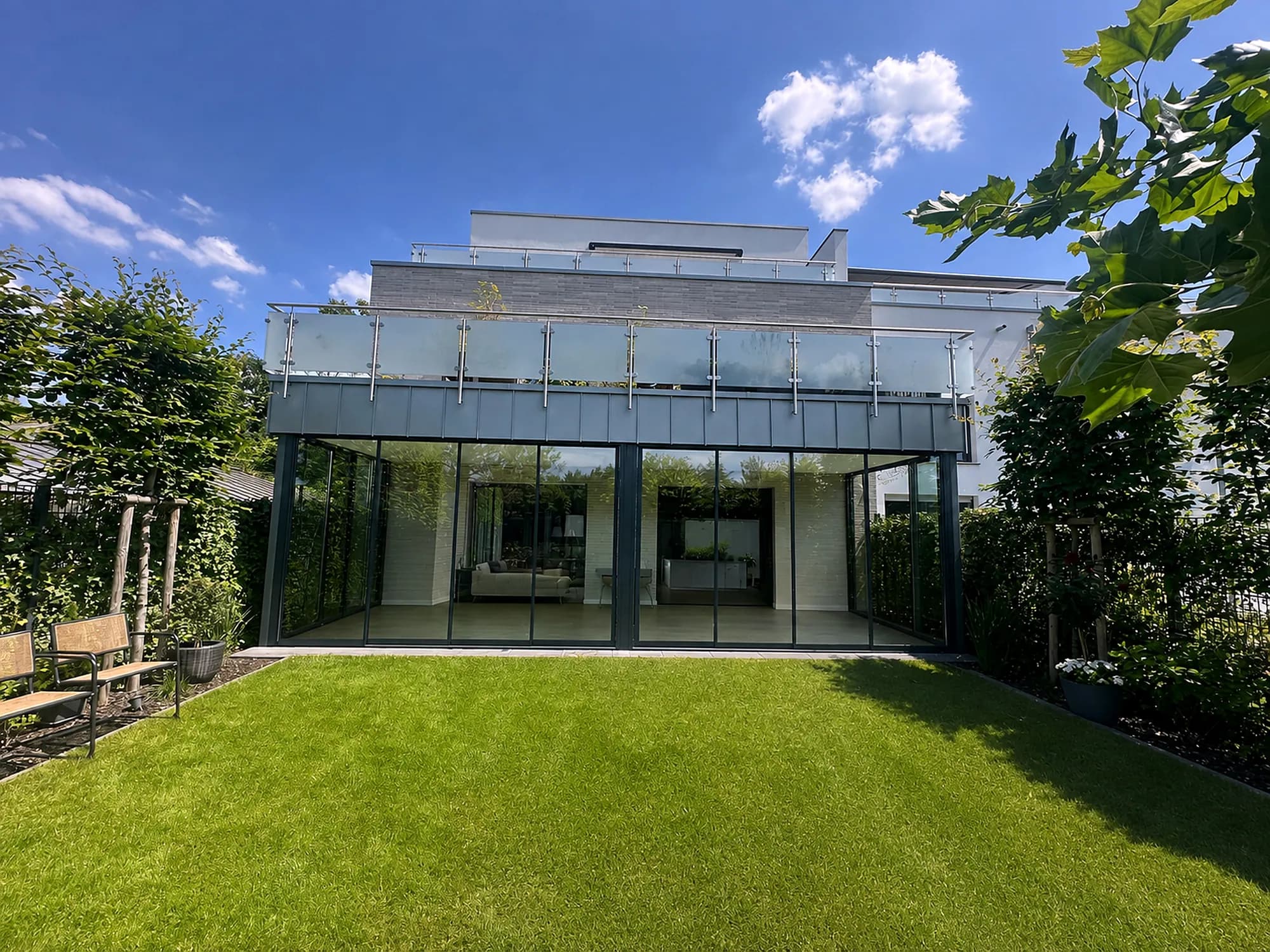 Glasanbau am Wohnhaus mit Dachterrasse und Glasgeländer darüber