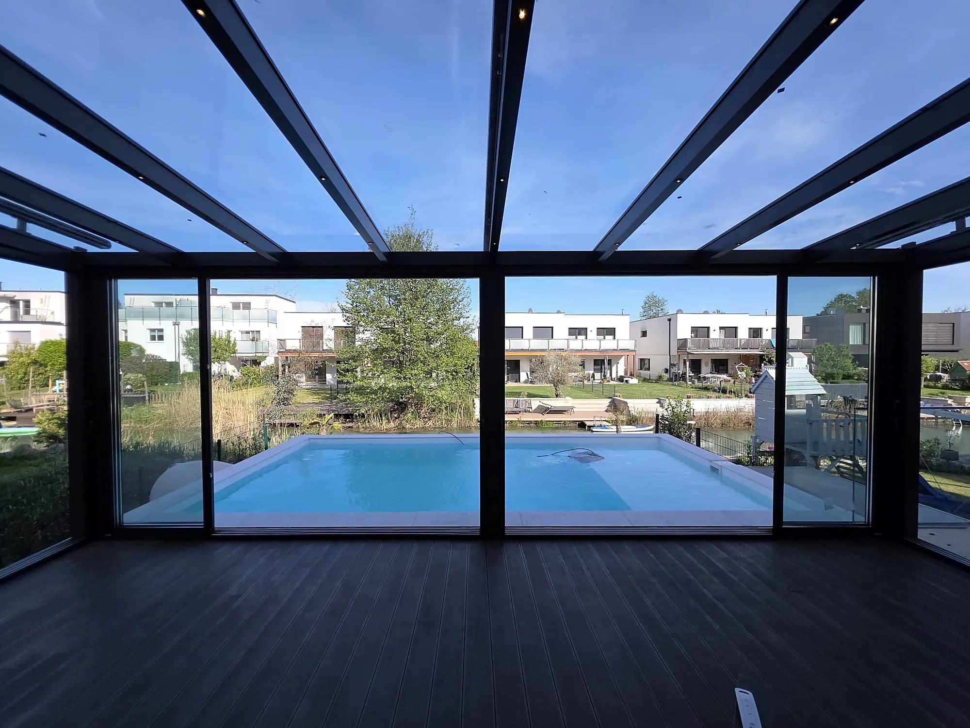Blick aus dem Glashaus durch die Verglasung auf Pool und Garten