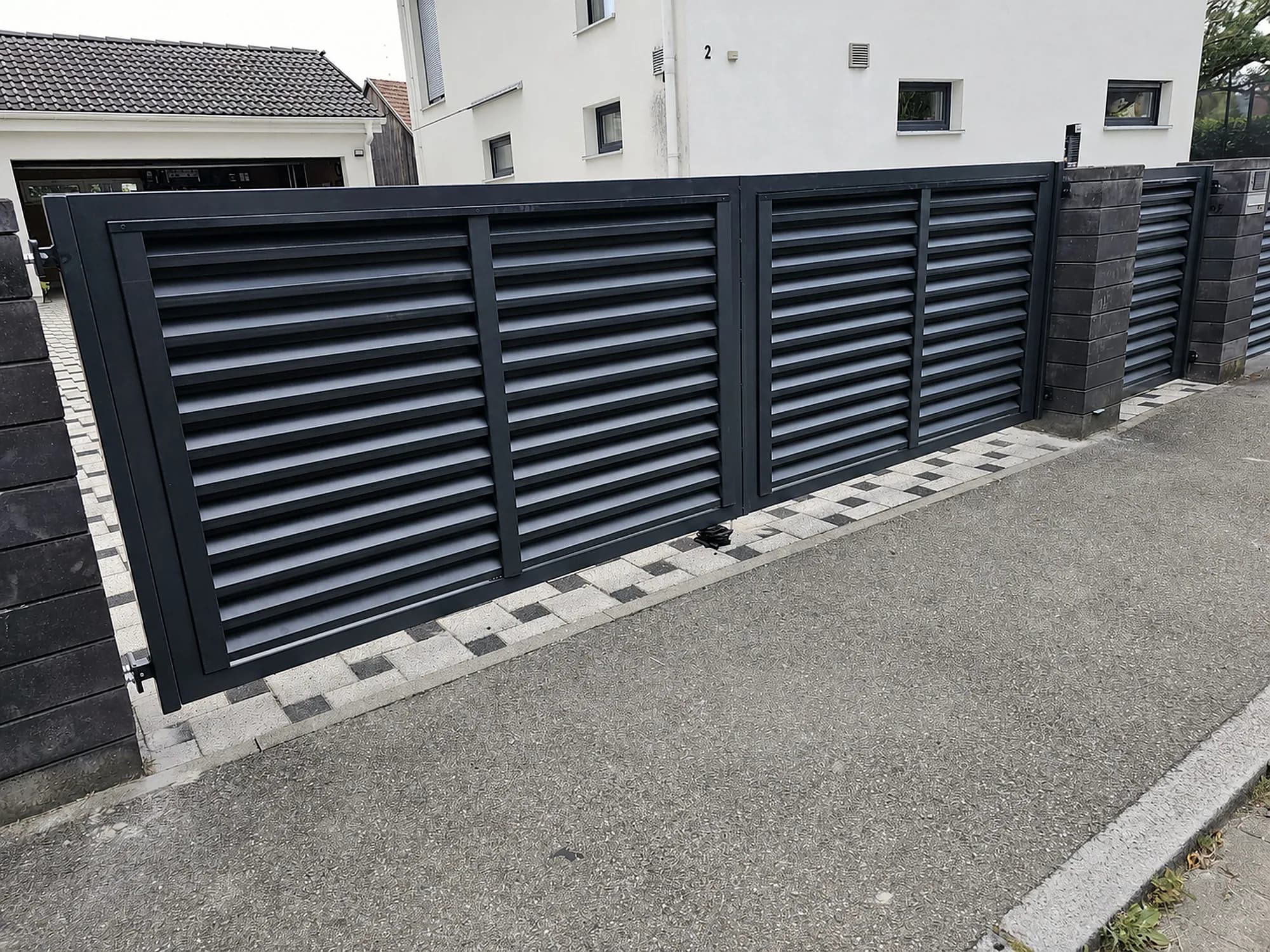 Anthrazitfarbener Lamellenzaun mit Einfahrtstor und Gartentür