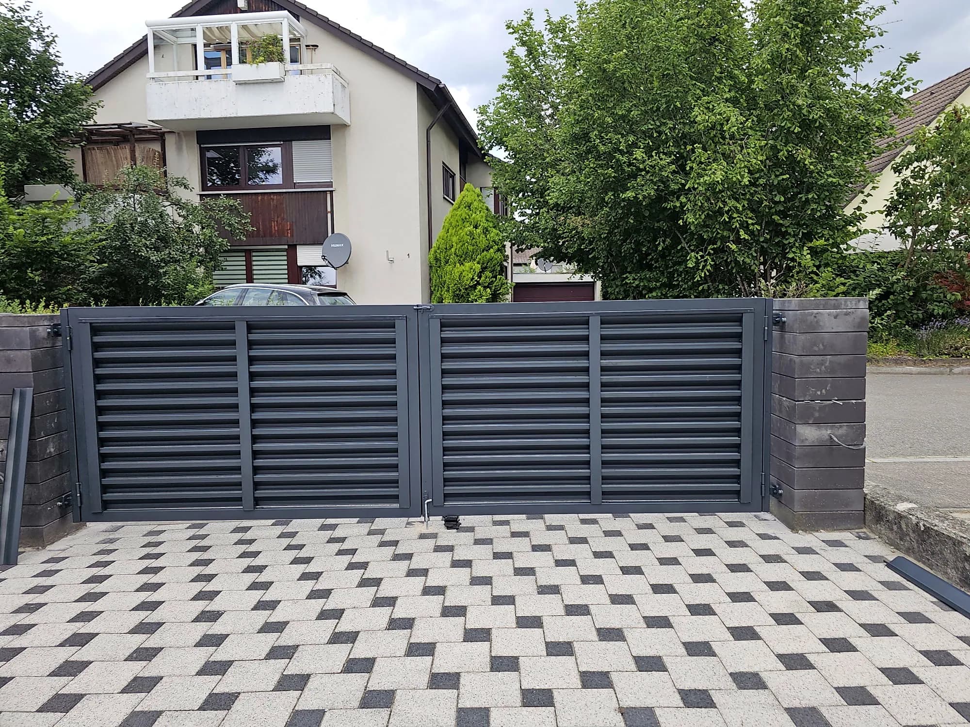 Lamellenzaun mit Doppeltor vor einem Wohnhaus